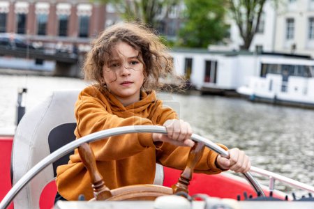 Foto de Una chica al timón de un barco en un canal en la ciudad de Amsterdam - Imagen libre de derechos