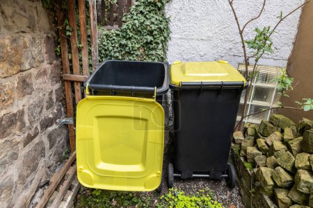 Photo for Two garbage cans for plastic stand in a yard in Germany, different types of garbage into different bins - Royalty Free Image