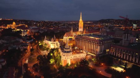 Téléchargez les photos : Drone 4K volant au Bastion des Pêcheurs illuminé par l'église Matthias avec tour d'horloge. Budapest, Hongrie - en image libre de droit