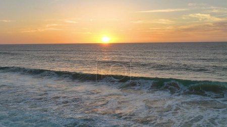 Téléchargez les photos : Mouvement lent de grandes vagues de l'océan Atlantique éclairées par la lumière du coucher du soleil. Drone cinématographique de coucher de soleil sur la mer. vue aérienne. - en image libre de droit