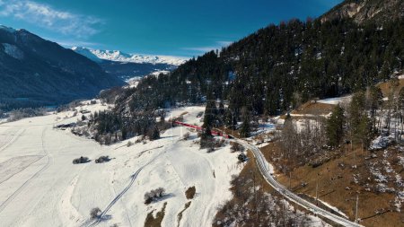 Téléchargez les photos : Vue aérienne du viaduc Landwasser et du Bernina express dans les Alpes suisses. Drone tourné train rouge passant par la montagne à Filisur, Suisse. - en image libre de droit
