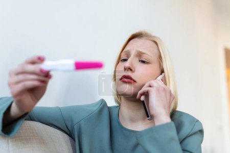 Femme choquée regardant la ligne de contrôle sur le test de grossesse. Femme triste célibataire se plaignant tenant un test de grossesse. Femme déprimée détenant un test de grossesse négatif.
