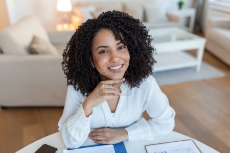 Photo for Portrait of a beautiful woman smiling at home. African woman in casual looking at camera with copy space. Cheerful mixed race girl relaxing at home with big laugh. - Royalty Free Image