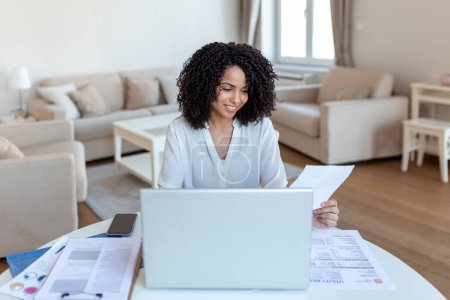 Photo for Business professionals. Business woman analyzing data using computer while spending time in the office. Beautiful young grinning professional Black woman in office. Graphs and charts - Royalty Free Image