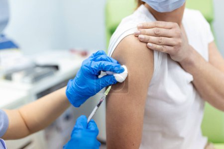 Téléchargez les photos : Praticien vaccinant une patiente en clinique. Médecin faisant une injection à une femme à l'hôpital. Infirmière tenant la seringue et injectant le vaccin Covid-19 ou le vaccin contre le coronavirus.. - en image libre de droit