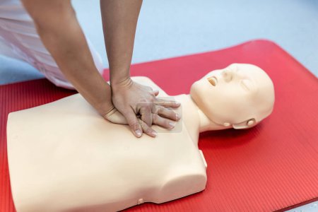 CPR training medical procedure - Demonstrating chest compressions on CPR doll in the class. First Aid Training - Cardiopulmonary resuscitation. First aid course on cpr dummy.