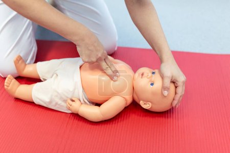 Téléchargez les photos : Femme effectuant une RCR sur une poupée d'entraînement pour bébé avec compression d'une main. Formation aux premiers soins - Réanimation cardiopulmonaire. Cours de premiers soins sur mannequin cpr. - en image libre de droit