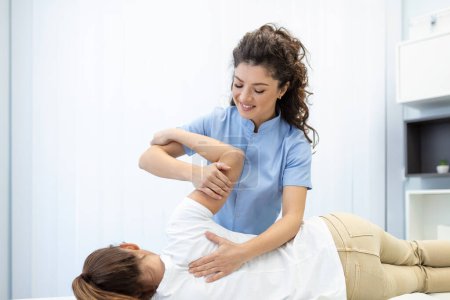 Photo for Close up of female osteopath doing shoulder blade therapy on young woman. - Royalty Free Image