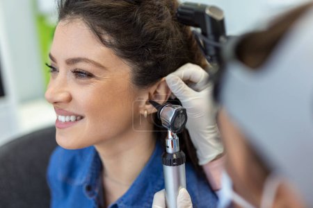 Foto de Acercamiento de una doctora sosteniendo cuidadosamente el oído de su paciente para establecer una visión más clara del interior de su oído, para ver si necesita audífonos en una clínica moderna - Imagen libre de derechos