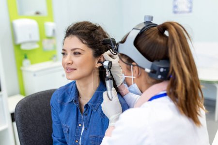 Examen auditif. Otolaryngologue médecin vérifiant l'oreille de la femme à l'aide d'un otoscope ou d'un auriscope à la clinique médicale. Otorhinolaryngologue tirant l'oreille avec la main et la regardant avec l'otoscope gros plan.
