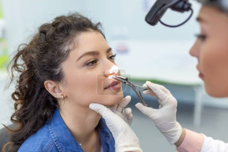 Concept d'otolaryngologie. Femme positive otorhinolaryngologue vérifier nez avec otoscope de son patient à l'hôpital. Congestion nasale, sinusite, concept d'allergie. Patiente à la clinique ORL moderne.