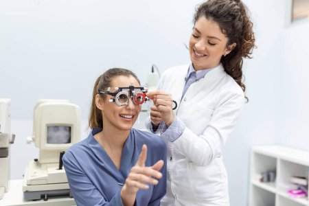 Foto de Los optometristas cambian las lentes en el marco del ensayo para examinar la visión de la paciente joven en la clínica de oftalmología, enfoque selectivo - Imagen libre de derechos