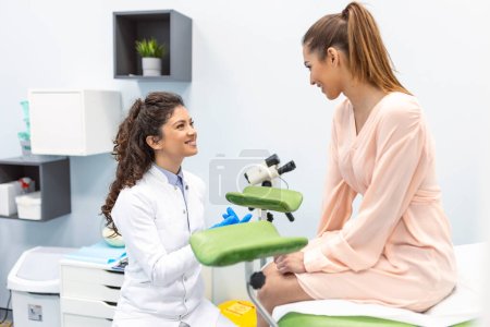 Téléchargez les photos : Gynécologue préparant une procédure d'examen pour une femme enceinte assise sur une chaise gynécologique dans le bureau - en image libre de droit