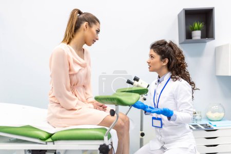Ginecólogo preparándose para un procedimiento de examen para una mujer embarazada sentada en una silla ginecológica en la oficina

