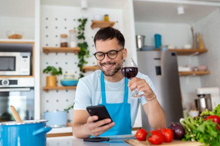 Photo for Happy young man preparing romantic dinner searching vegetable recipes diet menu cookbook app using smartphone, smiling husband holding phone cooking healthy vegan food cut salad in kitchen interior - Royalty Free Image