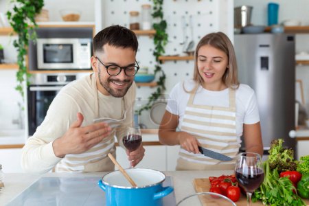 Téléchargez les photos : Romantique jeune couple cuisiner ensemble dans la cuisine, passer un bon moment ensemble. Homme et femme riant le matin avec petit déjeuner - en image libre de droit