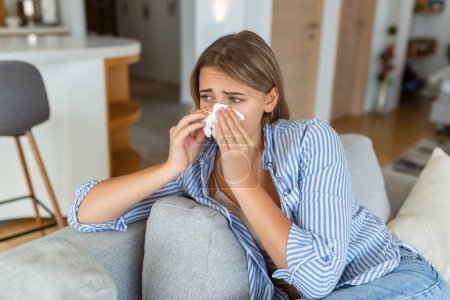 Photo for Sick desperate woman has flu. Rhinitis, cold, sickness, allergy concept. Pretty sick woman has runnning nose, rubs nose with handkerchief. Sneezing female. Brunette sneezing in a tissue - Royalty Free Image