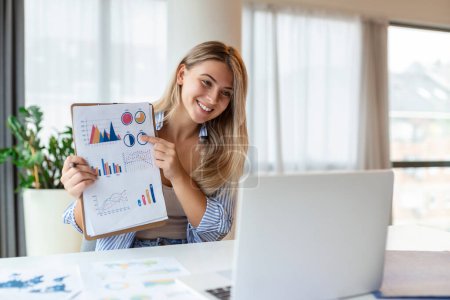 Photo for Focused business woman presenting charts and graphs on video call online. Young business woman having conference call with client on laptop. Young woman explaining how business work - Royalty Free Image