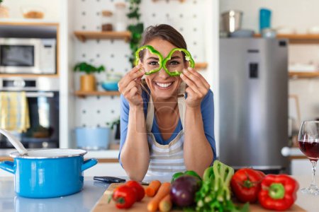 Photo for Photo of young woman smiling while cooking salad with fresh vegetables in kitchen interior at home - Royalty Free Image
