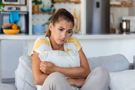 Photo for Anxious worried woman sitting on couch at home. Frustrated confused female feels unhappy, problems in personal life, quarrel break up with boyfriend and unexpected pregnancy concept - Royalty Free Image
