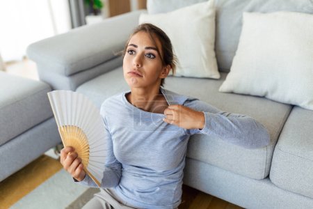 Stressé femme ennuyée en utilisant ventilateur ondulant souffrent de surchauffe, problème d'hormone de santé de chaleur d'été, la transpiration femme se sentent mal à l'aise chaud dans le problème de temps d'été sans climatiseur