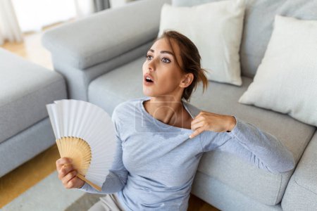 Mujer molesta estresada que usa ventilador ondulante sufren de sobrecalentamiento, problema de la hormona de salud del calor de verano, sudor de la mujer se siente incómodo caliente en el problema del clima de verano sin aire acondicionado