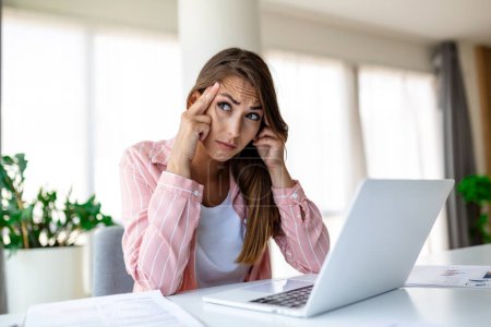 Photo for Exhausted businesswoman having a headache in modern office. Creative woman working at office desk feeling tired. Stressed casual business woman feeling head pain while overworking on desktop computer. - Royalty Free Image