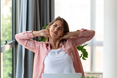 Photo for Feeling exhausted. Frustrated woman looking exhausted and massaging her neck while sitting at his working place - Royalty Free Image