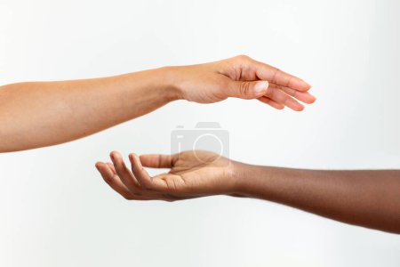 Foto de Manos con diferente color de piel, una afro-americana, una caucásica, tocándose sobre fondo gary. - Imagen libre de derechos