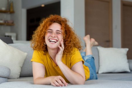 Photo for Young woman relaxing on her couch. Portrait of a beautiful woman smiling at home. woman in casual looking at camera with copy space. - Royalty Free Image