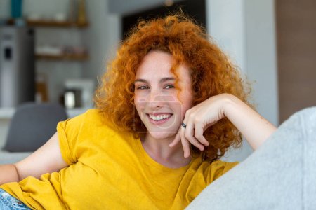 Photo for Young woman relaxing on her couch. Portrait of a beautiful woman smiling at home. woman in casual looking at camera with copy space. - Royalty Free Image