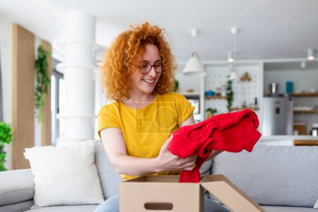 Photo for Young woman receiving parcel at home. Holiday shopping online and unpacking cardboard box. Delivery service during covid quarantine. Happy girl getting gift. Lifestyle moment - Royalty Free Image