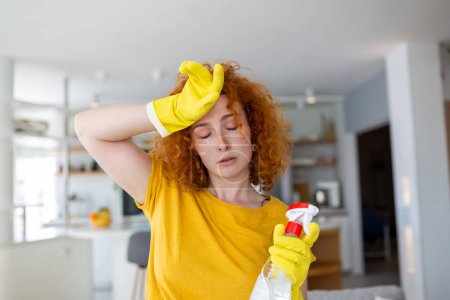 Téléchargez les photos : Portrait of young tired woman with rubber gloves resting after cleaning an apartment. Home, housekeeping concept. - en image libre de droit
