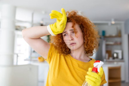Téléchargez les photos : Portrait of young tired woman with rubber gloves resting after cleaning an apartment. Home, housekeeping concept. - en image libre de droit