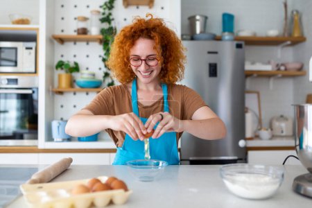 Téléchargez les photos : Concept de cuisson. Portrait de femme joyeuse malaxant la pâte dans l'intérieur de la cuisine, femme joyeuse dans le tablier s'amusant tout en préparant la pâtisserie maison, - en image libre de droit