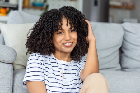 Photo for Portrait of a beautiful woman smiling at home. African woman in casual looking at camera with copy space. Cheerful mixed race girl relaxing at home with big laugh. - Royalty Free Image