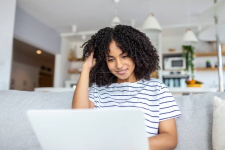 Téléchargez les photos : Chaud d'une jeune femme travaillant sur son ordinateur portable sur le canapé à la maison - en image libre de droit