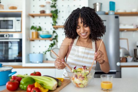 Photo for Healthy lifestyle. Good life. Organic food. Vegetables. Close up portrait of happy cute beautiful young woman while she try tasty vegan salad in the kitchen at home. - Royalty Free Image