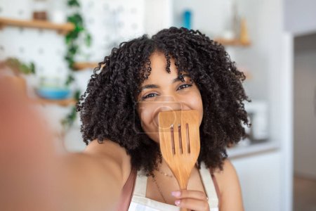 Foto de Joven mujer afroamericana bloguera de comida tomando una selfie con un soldador - Imagen libre de derechos