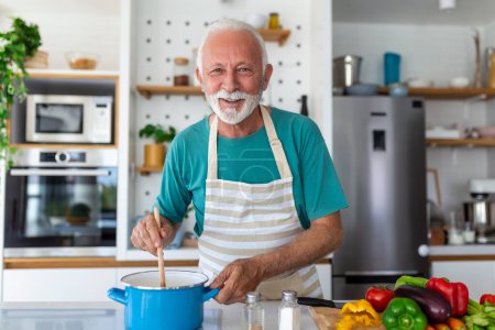 Photo for Happy senior man having fun cooking at home - Elderly person preparing health lunch in modern kitchen - Retired lifestyle time and food nutrition concept - Royalty Free Image