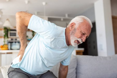 Téléchargez les photos : Homme âgé âgé touchant son dos, souffrant de maux de dos, sciatique, concept de mode de vie sédentaire. Problèmes de santé de la colonne. Soins de santé, assurances - en image libre de droit