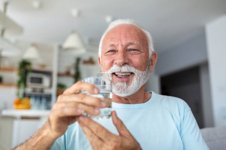 Foto de Un hombre mayor bebe agua de un vaso. Buena salud, estilo de vida. - Imagen libre de derechos