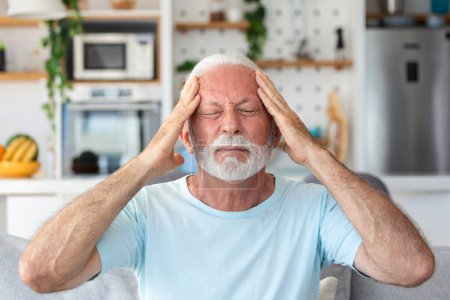 Téléchargez les photos : Mal de tête. Homme âgé souffrant de migraine Douleur Massage Temples assis à la maison. Soins de santé, problèmes de santé chez les personnes âgées Concept - en image libre de droit
