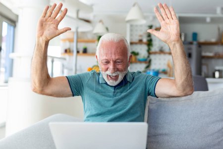 Téléchargez les photos : Homme âgé assis sur le canapé en regardant l'écran d'ordinateur portable crier de joie se sent heureux de célébrer la victoire de loterie, moment chanceux, a obtenu l'occasion en ligne, les ventes et les rabais concept de commerce électronique - en image libre de droit