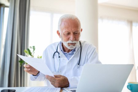 Photo for Serious old mature professional male doctor using laptop computer in hospital office having medical webinar training, writing in healthcare report, consulting patient online at telemedicine meeting. - Royalty Free Image