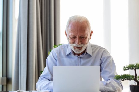 Foto de Asesor financiero hombre de negocios usando su computadora portátil y haciendo un poco de papeleo mientras está sentado en el escritorio y trabajando. - Imagen libre de derechos