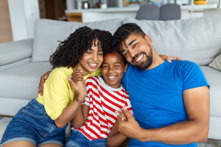Photo for Family sitting on sofa smiling at camera on modern apartment background Happy family with daughter playing at home and weekend for family - Royalty Free Image