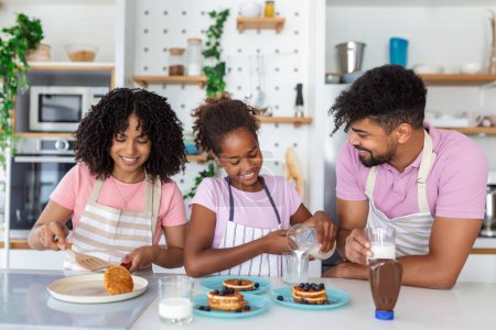 Photo for Overjoyed young family with little daughter have fun cooking baking pastry or pancakes at home together, happy smiling parents enjoy weekend play with small child doing bakery cooking in kitchen - Royalty Free Image