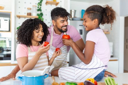 Photo for Mom, dad and daughter are cooking in kitchen. Happy family concept. Handsome man, attractive young woman and their cute little daughter are making salad together. Healthy lifestyle. - Royalty Free Image