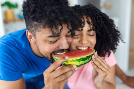 Téléchargez les photos : Gros plan de père joyeux et sa petite fille regardant heureux tout en mangeant pastèque ensemble. - en image libre de droit